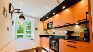 A modern kitchen with wooden cabinets, a black countertop, and a window with a view of greenery. - High-end flat in the centre of Gérardmer (Gérardmer)