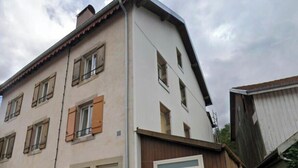 A two-story building with a garage door, a small porch, and a single visible window. - High-end flat in the centre of Gérardmer (Gérardmer)