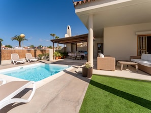 A rooftop pool area with lounge chairs, a dining set, and a covered patio.