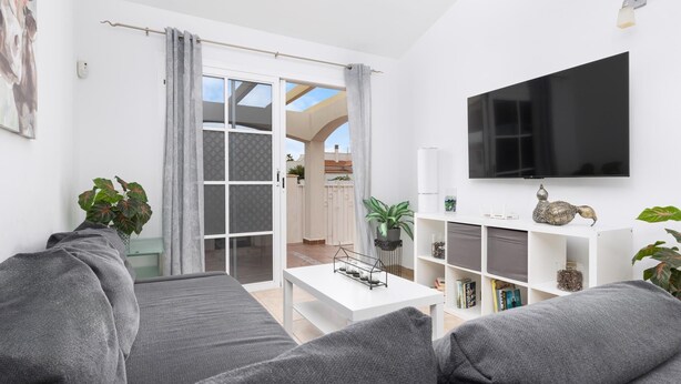 A modern living room with grey sofas, a white coffee table, and a flat-screen TV mounted on the wall. - Vivelorural Las Coquetas, Caleta de Fuste (Antigua)