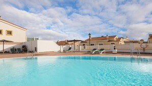 A swimming pool with clear blue water, surrounded by white buildings with red-tiled roofs. - Vivelorural Las Coquetas, Caleta de Fuste (Antigua)
