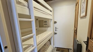 A bunk bed room with a door and a small mat at the entrance. - Studio with balcony - near lake (Les Deux Alpes)