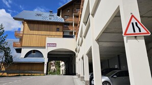A multi-story building with a wooden facade, a sign reading "LES PLEIADES," and a road sign indicating a narrow road ahead. - Studio with balcony - near lake (Les Deux Alpes)