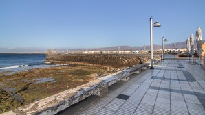 A coastal promenade with a stone wall, tiled walkway, and street lamps. - Holiday Home 'Us' with Private Terrace and Wi-Fi (Arinaga)
