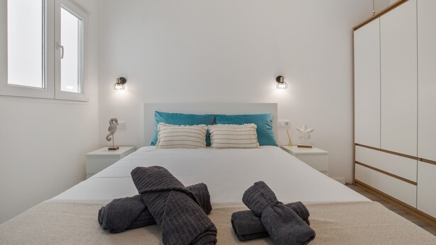 A hotel room with a bed, two bedside tables, a nightstand, a wardrobe, and a window. - Holiday Home 'Us' with Private Terrace and Wi-Fi (Arinaga)