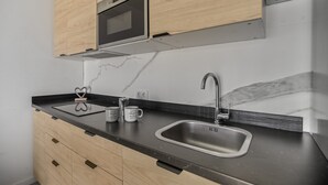 A modern kitchen with wooden cabinets, a stainless steel sink, and a built-in oven. - Holiday Home 'Us' with Private Terrace and Wi-Fi (Arinaga)