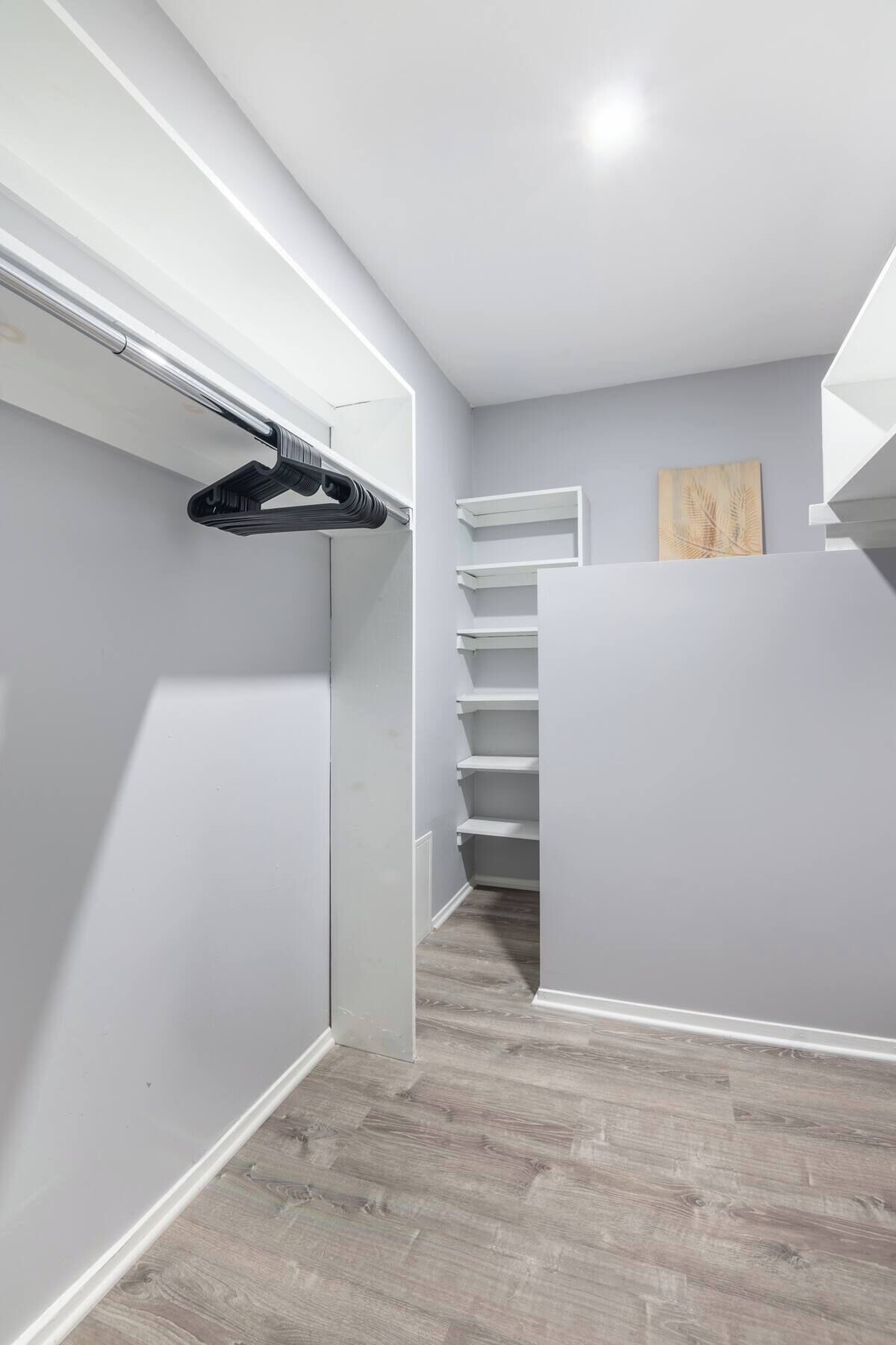 Ein moderner, gut beleuchteter Flur mit Holzboden, weißen Wänden und einem eingebauten Kleiderschrank mit Regalen.