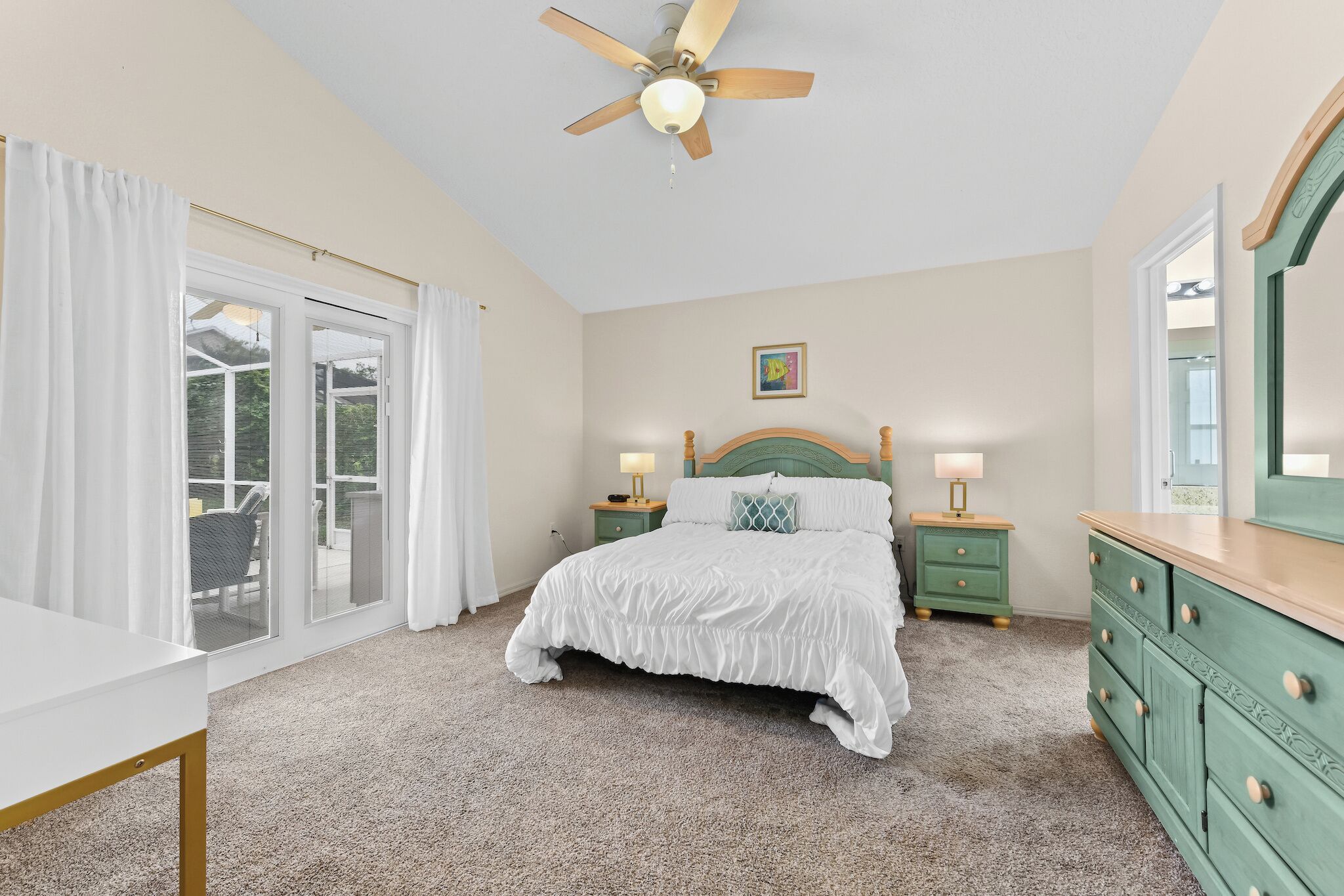 A bedroom with a bed, nightstands, a dresser, a ceiling fan, and a sliding glass door leading to an outdoor area.