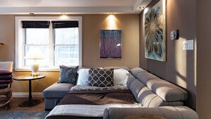 Et moderne soveværelse med seng, sofa, et lille bord og billedkunst på væggene.