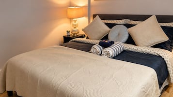 Un lit bien fait, avec une couverture à motifs, des oreillers et des serviettes enroulées.
