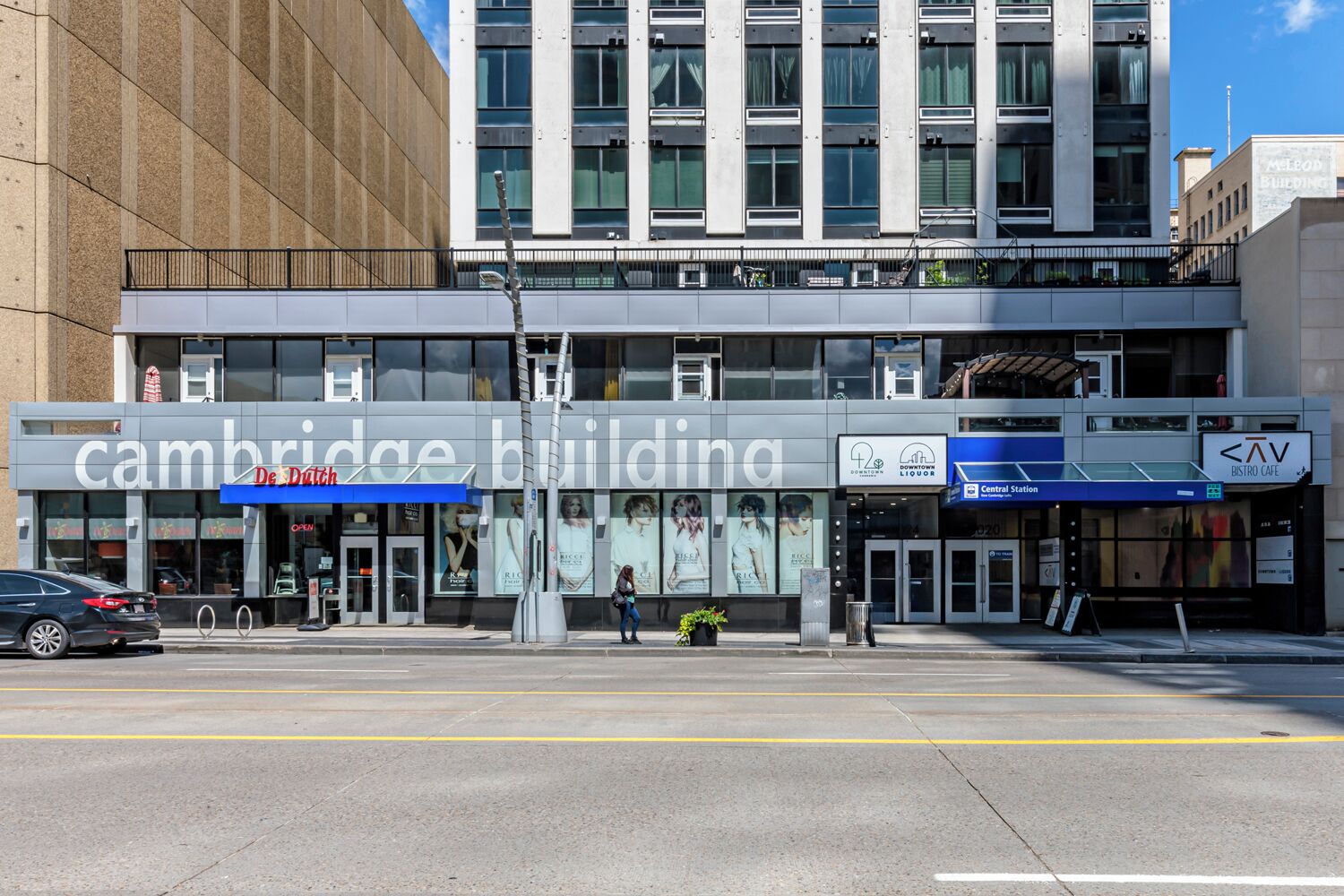 Un bâtiment moderne avec une enseigne indiquant « Cambridge Building », une autre indiquant « Downtown Liquor » et une troisième indiquant « Central Station ».