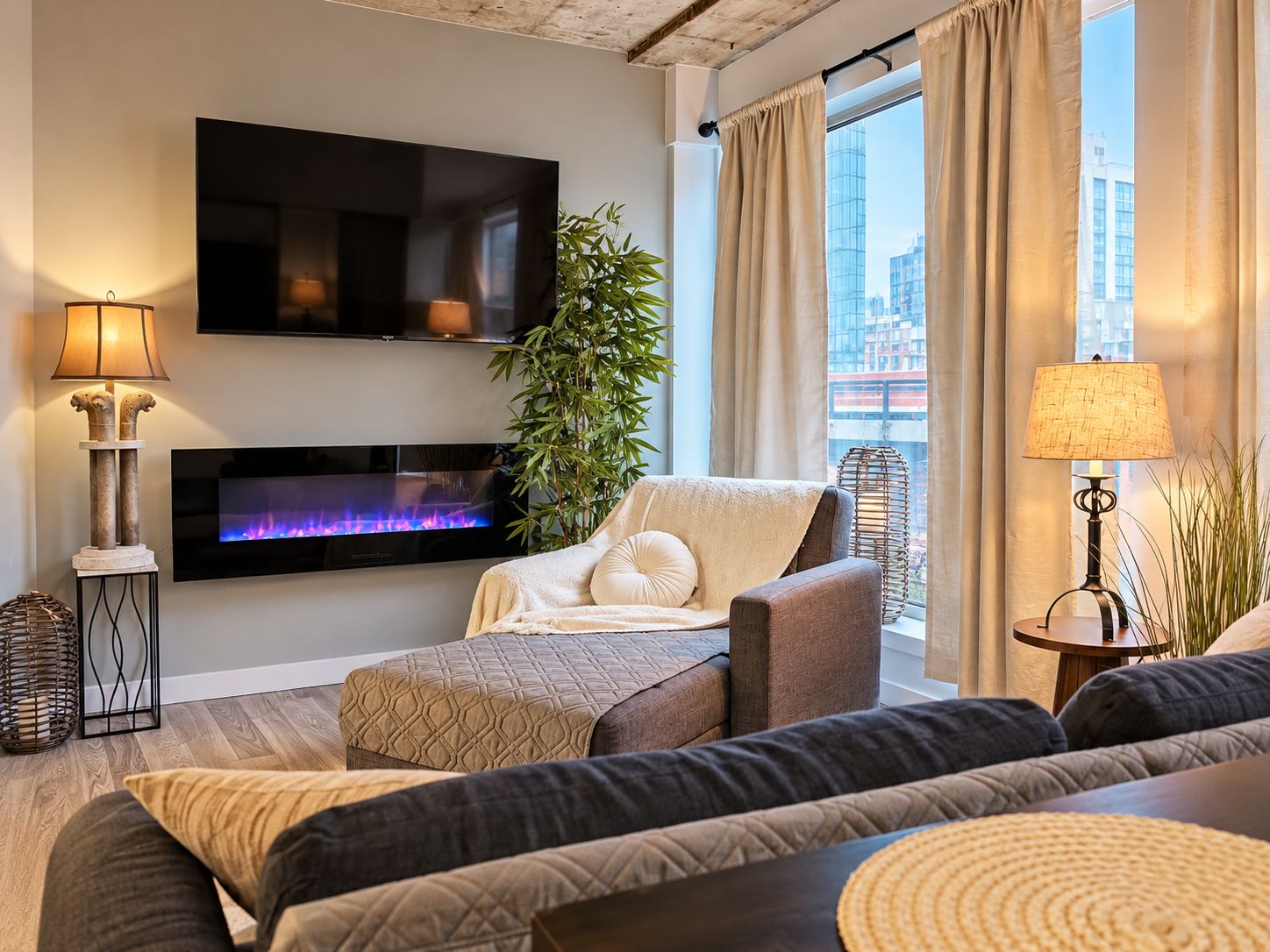 Un salon moderne doté d’un téléviseur à écran plat, d’une cheminée, d’un canapé confortable et offrant une vue sur la ville.