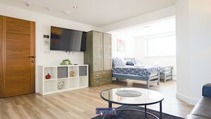 Un dormitorio moderno con cama, televisor, armario y una mesita.