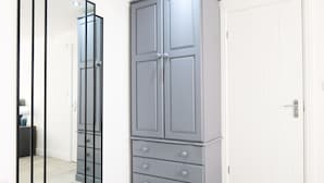 Una habitación con un armario gris, una puerta blanca y un espejo.