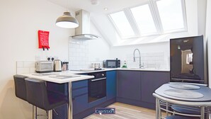 Una cocina moderna con comedor, lavavajillas Bosch, microondas y pileta.