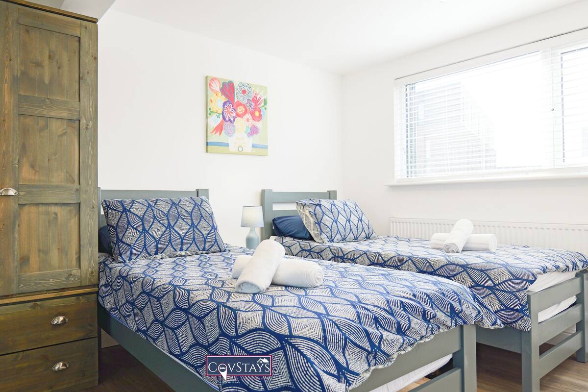 Ein Schlafzimmer mit zwei Betten, einem Holzschrank und einem Fenster mit Jalousien.