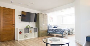 Een moderne slaapkamer met een bed, een televisie, een kledingkast en een klein tafeltje.