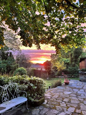A stone pathway leading to a rustic building with a metal bench and a potted plant. - COUNTRY HOUSE (Paulinet)