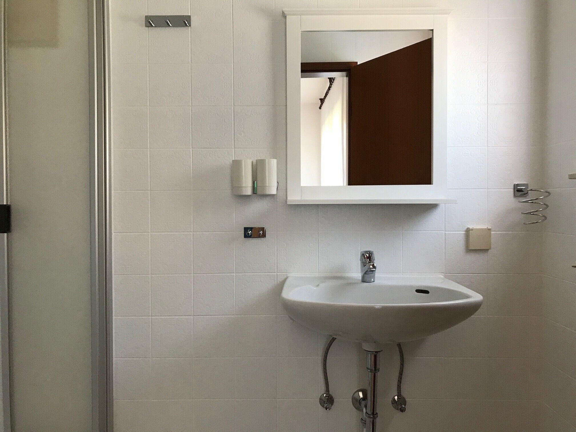 A bathroom with a white sink, a mirror, and a towel rack.