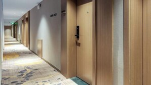 Un pasillo de hotel con puertas de madera, suelo alfombrado y un cartel que indica los números de las habitaciones.