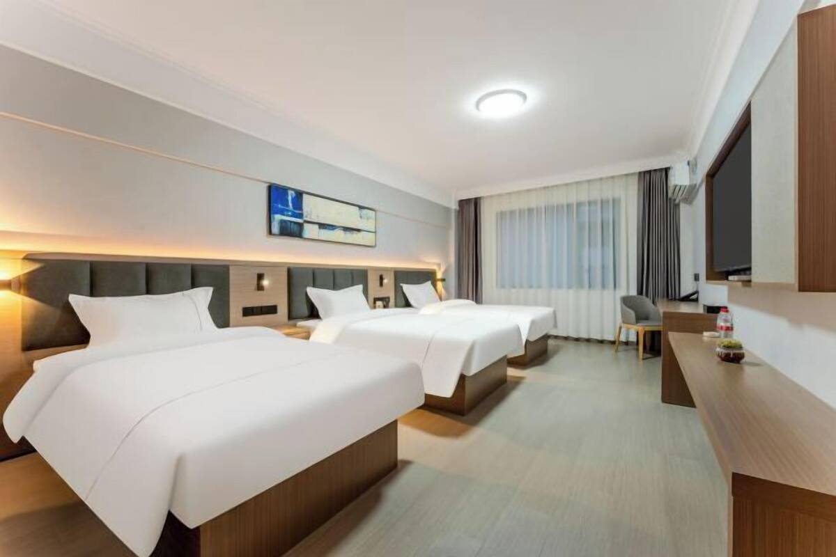 A hotel room with two beds, a desk, a chair, and a television.