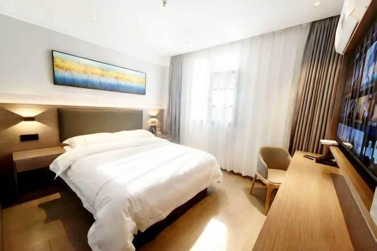 A hotel room with a large bed, bedside tables, a desk, and a TV.