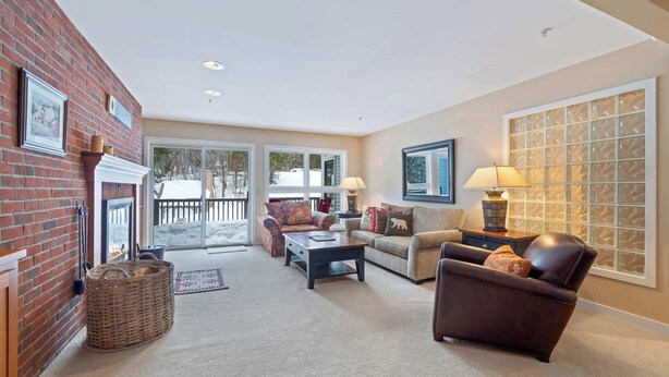 A cozy living room with a fireplace, comfortable seating, and large windows. - Ski-In/Out at Okemo | 3BR Ledgewood w/ Fireplace (Ludlow)