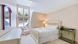 A bedroom with a bed, bedside table, lamp, and a green nightstand. - Ski-In/Out at Okemo | 3BR Ledgewood w/ Fireplace (Ludlow)