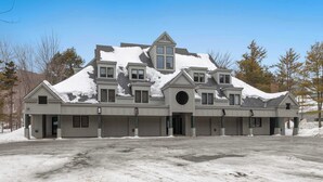 A multi-story house with a garage, a covered driveway, and a snow-covered roof. - Ski-In/Out at Okemo | 3BR Ledgewood w/ Fireplace (Ludlow)