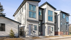 A modern multi-story residential building with a flat roof, large windows, and a visible address number. - Ultimate Group Stay, 3 King Beds, 2 Suites (Calgary)