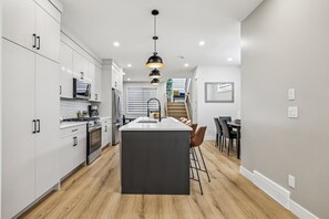 Uma cozinha moderna com armários brancos, uma ilha central e uma área de refeições com cadeiras.