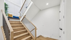 A staircase with wooden steps and black railings leading to a landing with a bench. - Ultimate Group Stay, 3 King Beds, 2 Suites (Calgary)