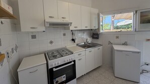 Une cuisine avec des armoires blanches, une cuisinière à gaz, un évier et un réfrigérateur.