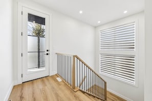 Una escalera con barandilla de madera y una puerta blanca con ventana de vidrio esmerilado.