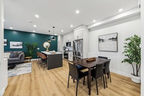 A modern kitchen with a central island, white cabinetry, and stainless steel appliances. - Rare Find-Dual Suites, 3 Kings & Prime Location (Calgary)