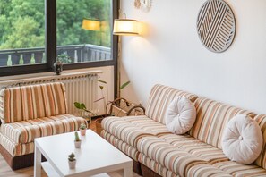 Ein gemütliches Wohnzimmer mit gestreifter Couch, einem weißen Couchtisch und einer Stehlampe.