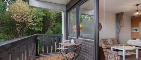 Een balkon met een houten tafel, stoelen, een bank en een plant in een pot.