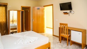 Ein Hotelzimmer mit Bett, Schreibtisch, Stuhl, Fernseher und Kleiderschrank.