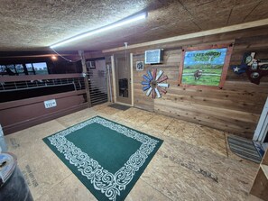 Ein Zimmer mit Holzbalkendecke, einem grün gemusterten Teppich, einer Windmühlen-Dekoration und einem Bilderrahmen mit einer Kuh auf einer Wiese.