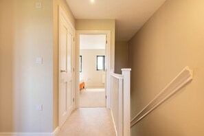 A hallway with a staircase leading to a bedroom.