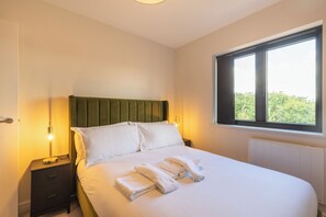 Habitación de hotel con cama, dos mesitas de noche, ventana con vistas y un radiador.
