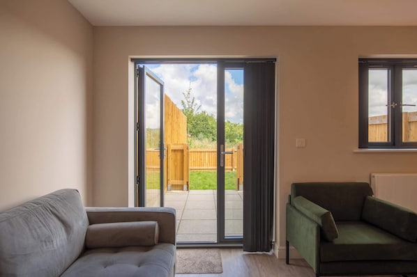 A living room with a sliding glass door leading to a patio, a grey sofa, and a green armchair.