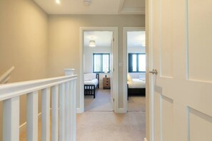 A hallway leading to a bedroom with a bed, a nightstand, and a window. - Newly Refurbished Home, Short Drive to Bath Centre (Bath and North East Somerset)
