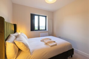 A bedroom with a bed, pillows, a window, and a radiator.