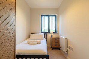 A bedroom with a bed, a nightstand, a window with blinds, and a radiator. - Newly Refurbished Home, Short Drive to Bath Centre (Bath and North East Somerset)