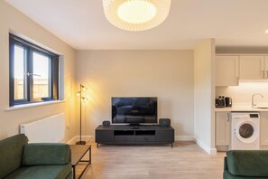 A modern living room with a flat-screen TV, a floor lamp, and a sofa.