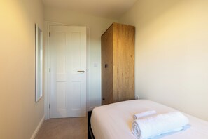 A hotel room with a bed, a wooden wardrobe, and a white door.