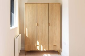 A room with a tall, light wooden wardrobe, a radiator, and a window casting shadows. - Newly Refurbished Home, Short Drive to Bath Centre (Bath and North East Somerset)