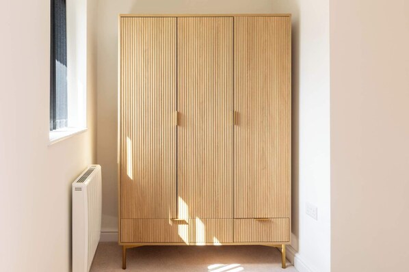 A room with a tall, light wooden wardrobe, a radiator, and a window casting shadows. - Newly Refurbished Home, Short Drive to Bath Centre (Bath and North East Somerset)