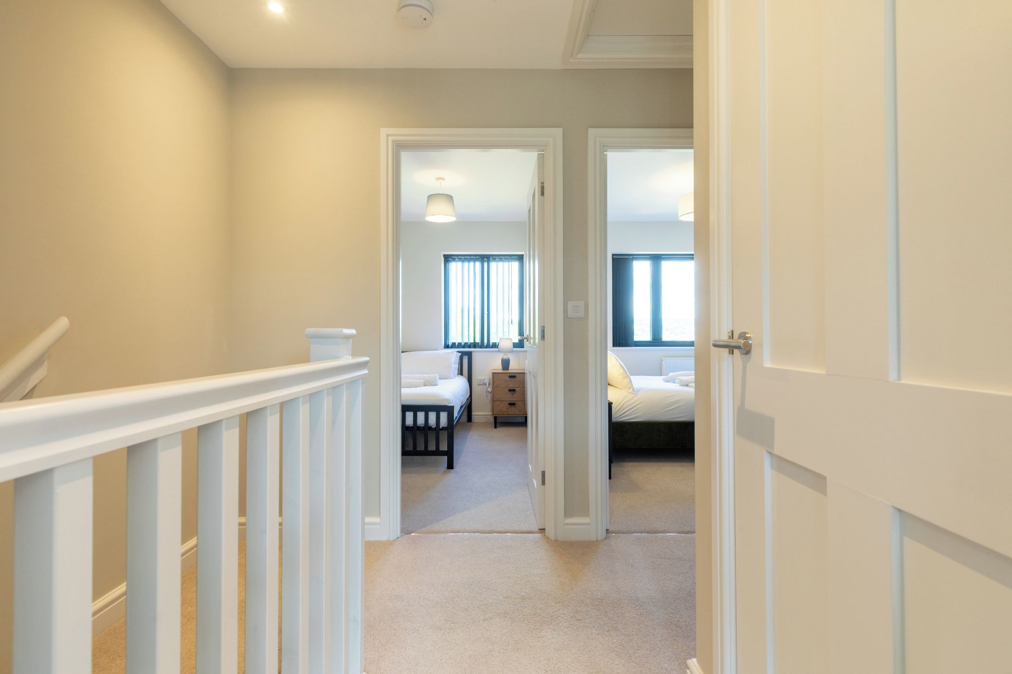 A hallway leading to a bedroom with a bed, a dresser, and a window.